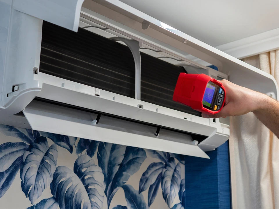 Hvac technician using thermal imager inspecting air conditioner filter for temperature and efficiency in a home or office setting, ensuring optimal cooling performance