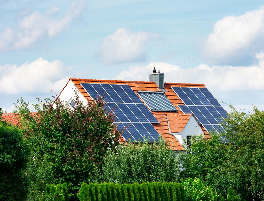 Maison résidentielle avec toiture en tuiles terre cuite équipée de panneaux solaires photovoltaïques et chauffe-eau solaire